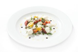 Pesce marinato su letto di rucola con capperi, pomodorini e mozzarella
