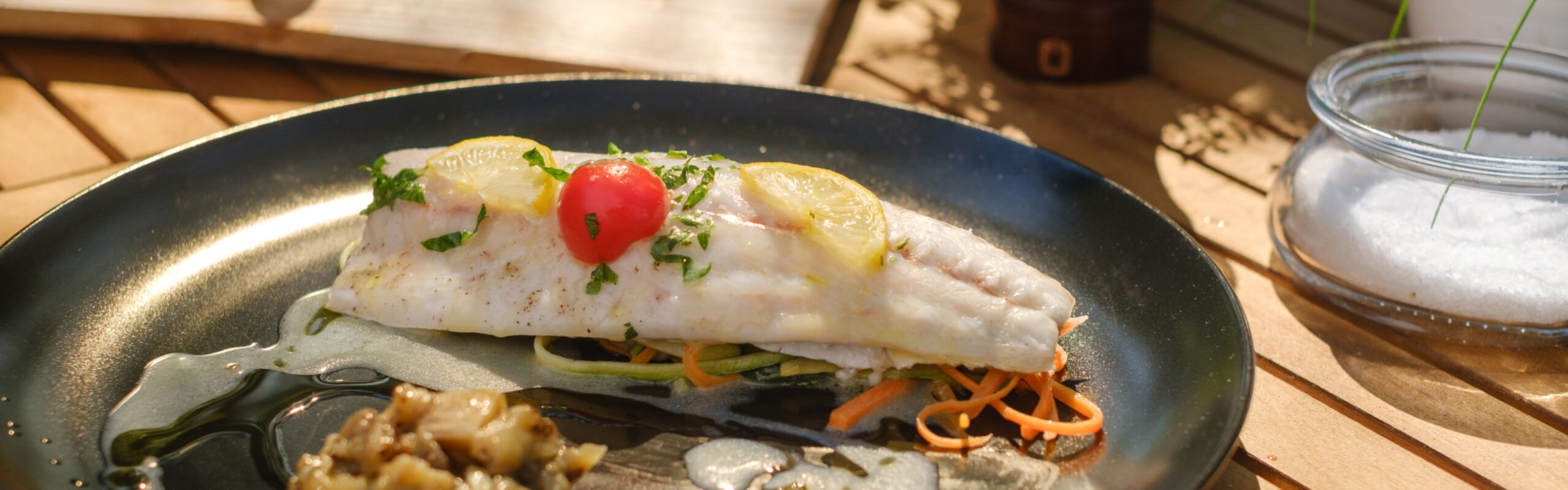Filetti di branzino sulla tavoletta di legno di cedro per barbecue